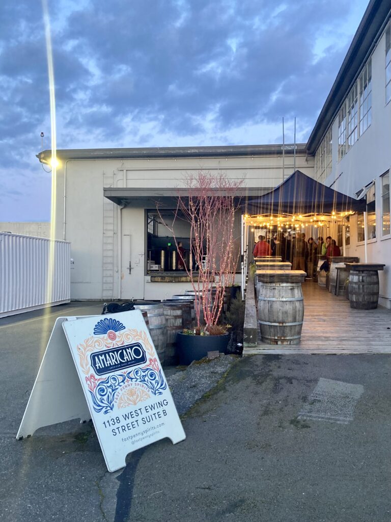 A twilight view of the outdoor entrance of Fast Penny Spirits in North Queen Anne.